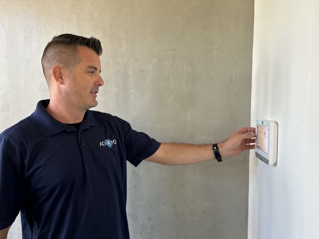 Man inspects alarm outside of building in Adamo shirt